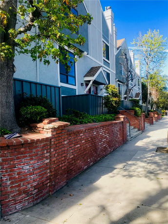 Front view of a multi-story residential building with brick fencing.
