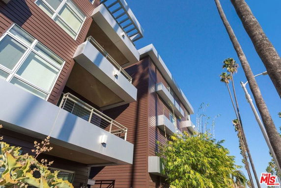 Angled view of a modern multi-story building with balconies and large windows.