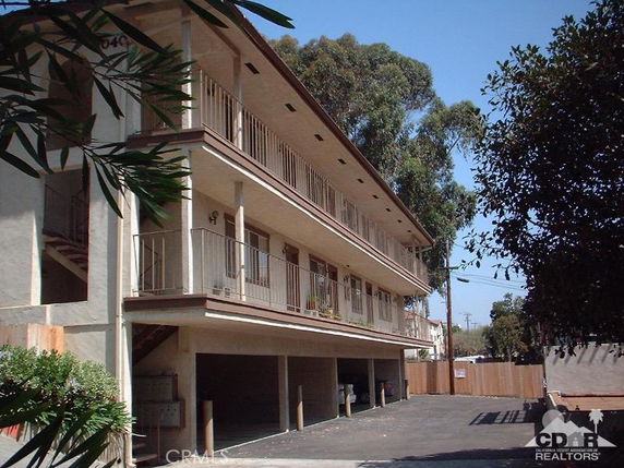 Side view of a multi-story apartment building with outdoor parking area.
