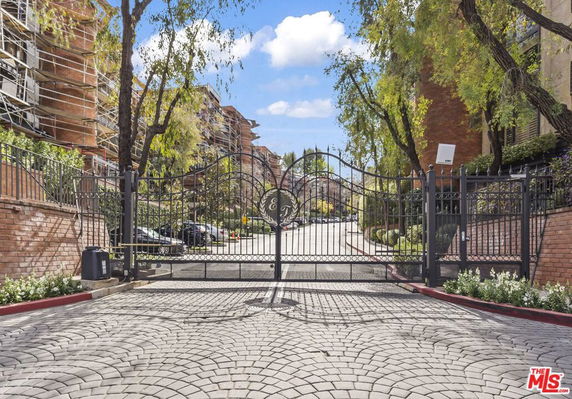 Gated entrance to a residential complex with multi-story buildings.