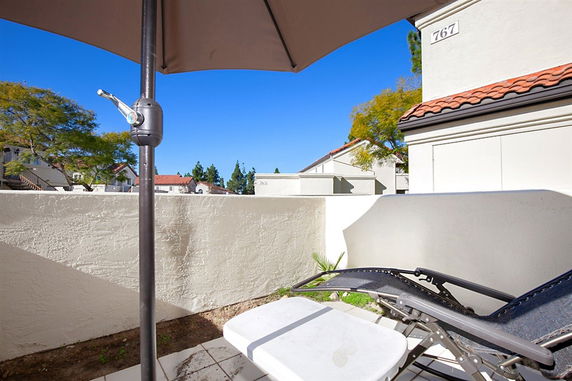 View from a patio showing neighboring buildings and a clear sky.