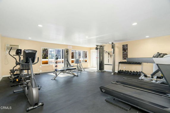 Indoor gym with exercise equipment including treadmills, exercise bikes, and weightlifting machines.