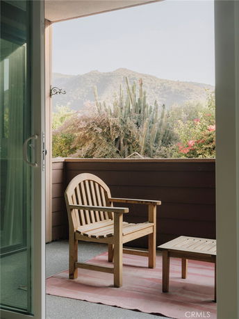 View of surrounding hills from a balcony with a wooden chair and table.