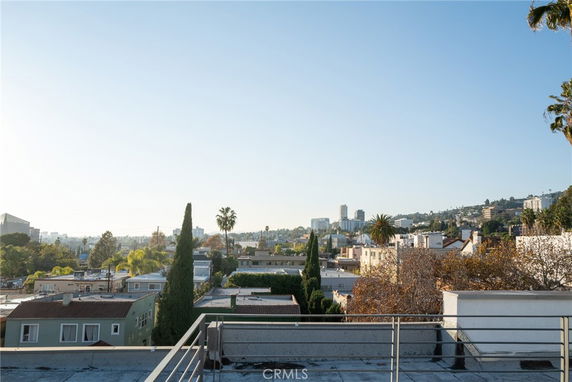 Panoramic view of cityscape from a rooftop showing various buildings and trees.