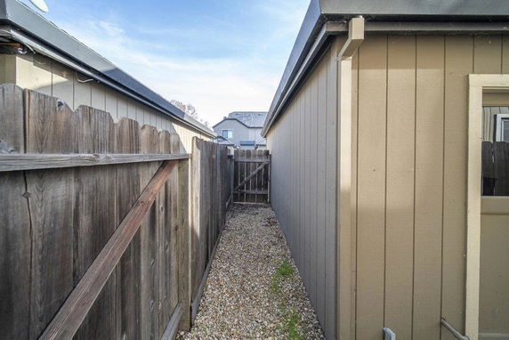 Side view of a building with wooden paneling and adjacent fence.