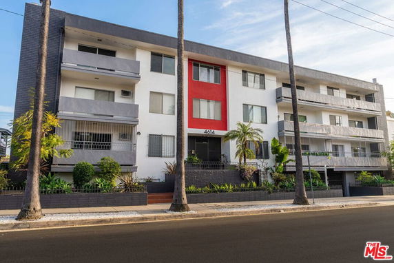 Front view of a multi-story residential building with balconies and a central red accent.