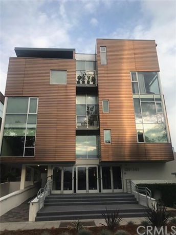 Front view of a modern multi-story building with large windows and wooden paneling.