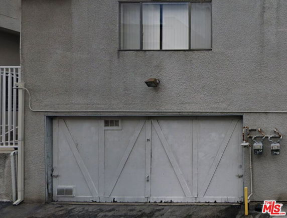 Front view of a garage with a window above and a light fixture.