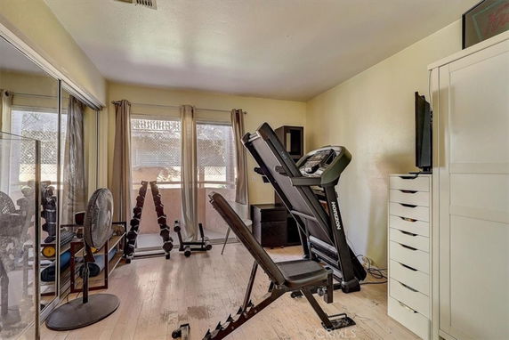 Room equipped with gym equipment including a treadmill and weights.