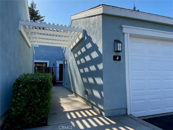 Front view of a house entrance with a garage and a white trellis.