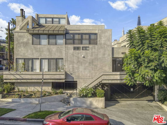 Front view of a multi-story residential building with a concrete exterior and gated entry.