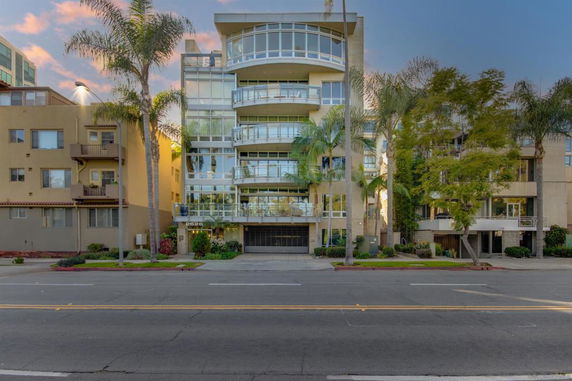 Front view of a multi-story modern building with large glass windows and balconies.