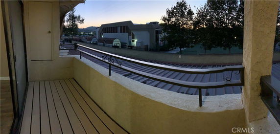 Balcony view overlooking surrounding buildings and distant hills.