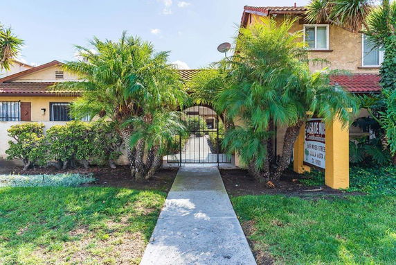 Front view of a residential building with a garden and gated entrance.