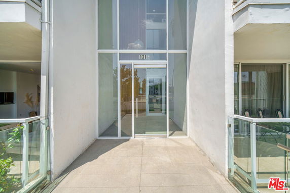 Front view of a modern building with glass entrance and balconies.