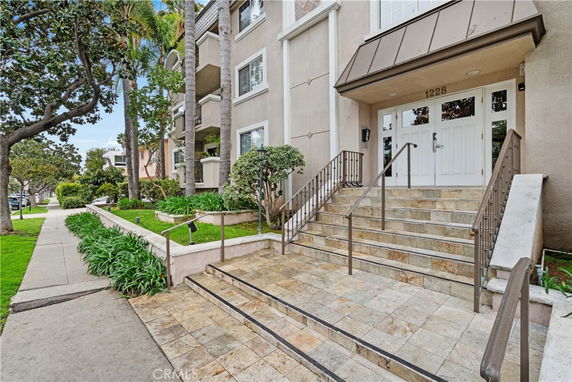 Front view of a multi-story building with a staircase entrance and landscaped surroundings.