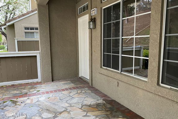 Front view of a house with a stone-paved entrance and large windows.