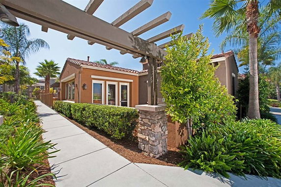 Front view of a single-story house with stone and stucco design and a pergola.