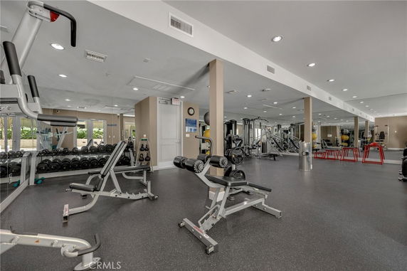 Gym area with various exercise equipment and mirrored walls.