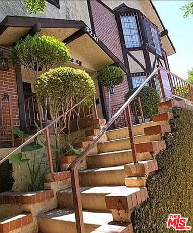 Front view of a multi-story house with brick and timber detailing.