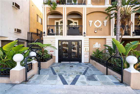 Front view of a building entrance with decorative elements and balcony railings.