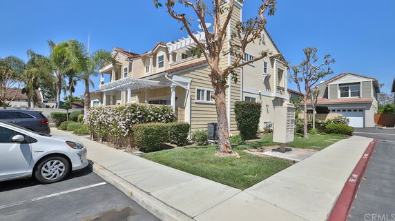 Front view of a two-story house with a porch and adjacent parking area.
