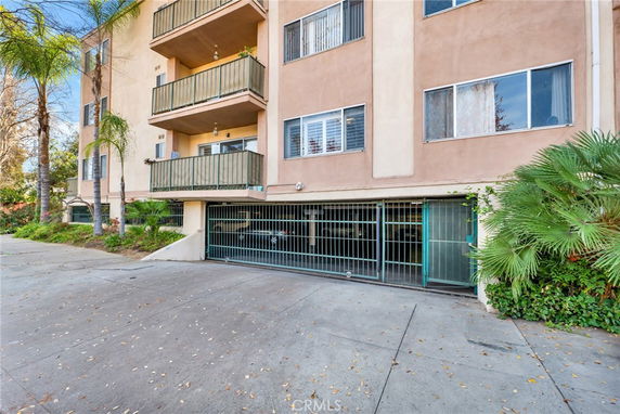 Front view of a multi-story apartment building with a gated parking area.