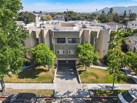 Front view of a multi-story residential building with garage and trees in front.
