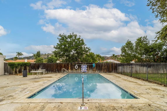 Outdoor swimming pool with surrounding fence and patio area.