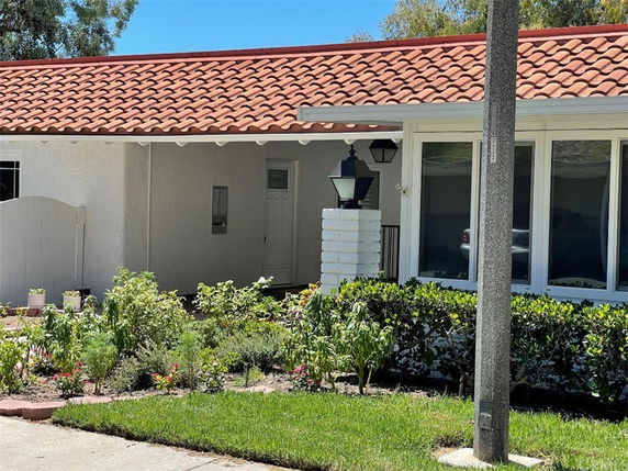 Front view of a house with a red-tiled roof and white walls.