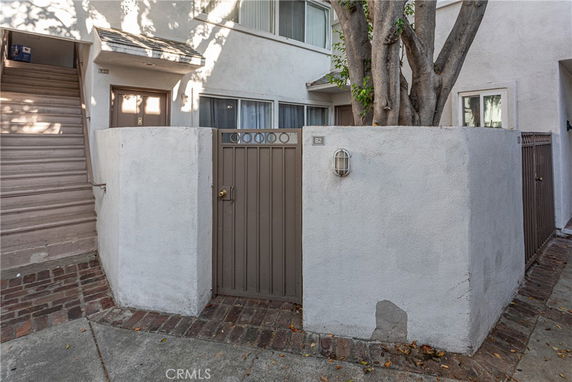 Front view of an apartment entrance with stairs and a gated area.