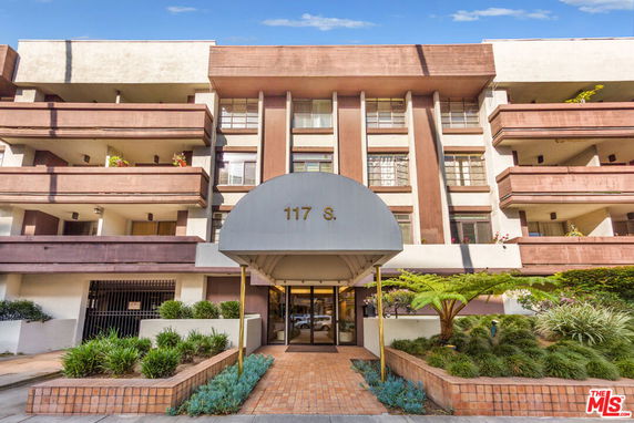 Front view of a multi-story residential building with balconies and an entrance canopy.