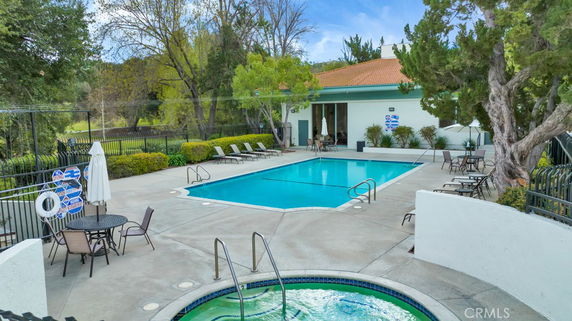 Outdoor swimming pool area with lounge chairs and greenery.
