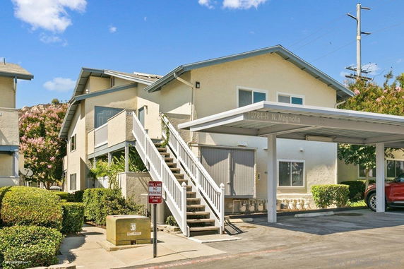Front view of a two-story house with an exterior staircase and covered parking area.