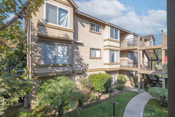 Front view of a three-story apartment building with balconies and external staircases.