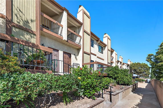 Front view of a multi-story building with balconies and a walkway.