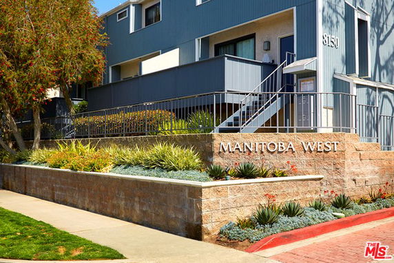 Front view of a multi-story building with a staircase and Manitoba West signage.