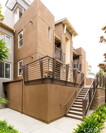 Front view of a multi-story house with modern design elements and a staircase leading to the entrance.