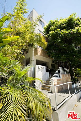 Front view of a multi-story building with a modern design and a staircase.