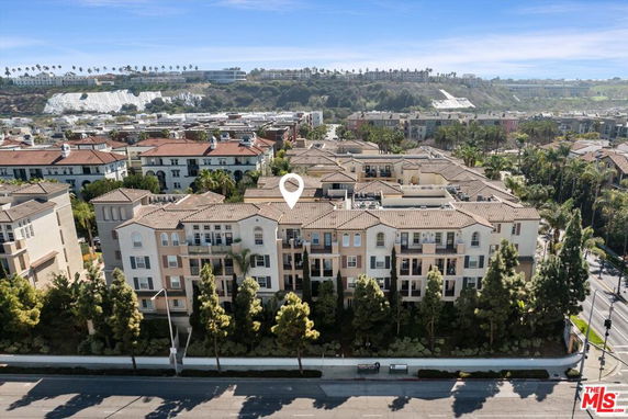 Aerial view of a multi-story residential building with surrounding landscape and buildings.