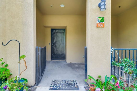Front view of an entrance to a residential building with a metal door and a small patio area.