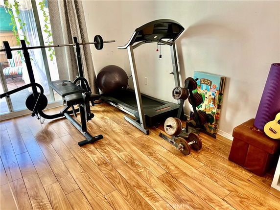 Home gym area with exercise equipment, including a treadmill, weights, and workout bench.