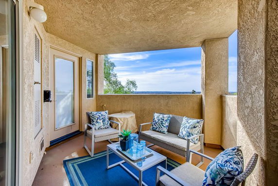 Outdoor seating area on a balcony with a panoramic view of the sky and ocean.