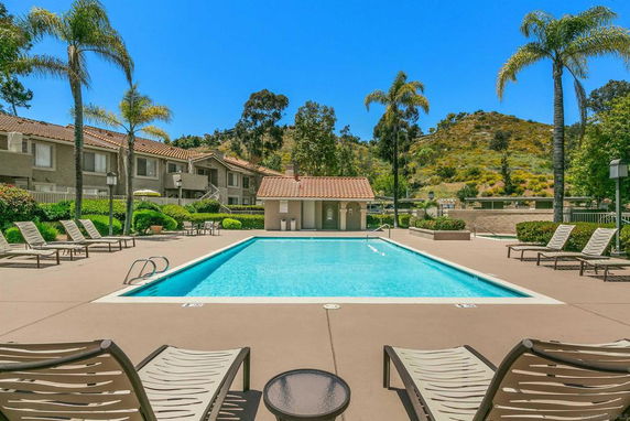Outdoor swimming pool area with lounge chairs and surrounding landscape.