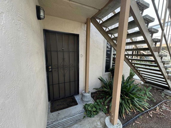Outdoor entrance with a security door beneath an external staircase.