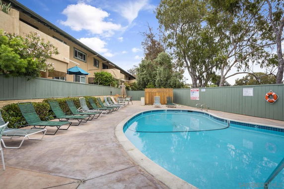 Outdoor swimming pool area with lounge chairs and surrounding fence.