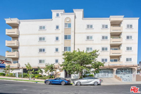 Front view of a multi-story apartment building with balconies and garage entry.