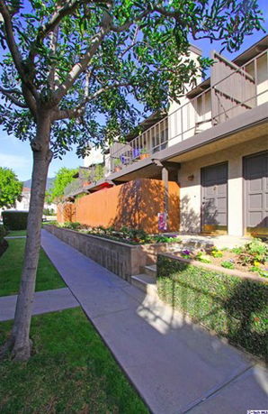 Front view of a multi-story building with balconies and a landscaped walkway.