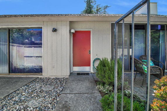 Front view of a single-story house with a red door and large windows.