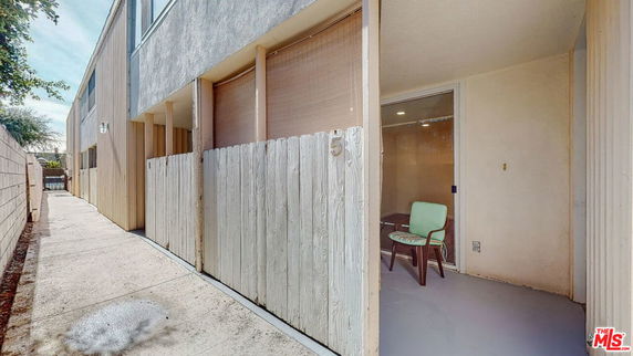 Front view of a building with enclosed patio and wooden fence.